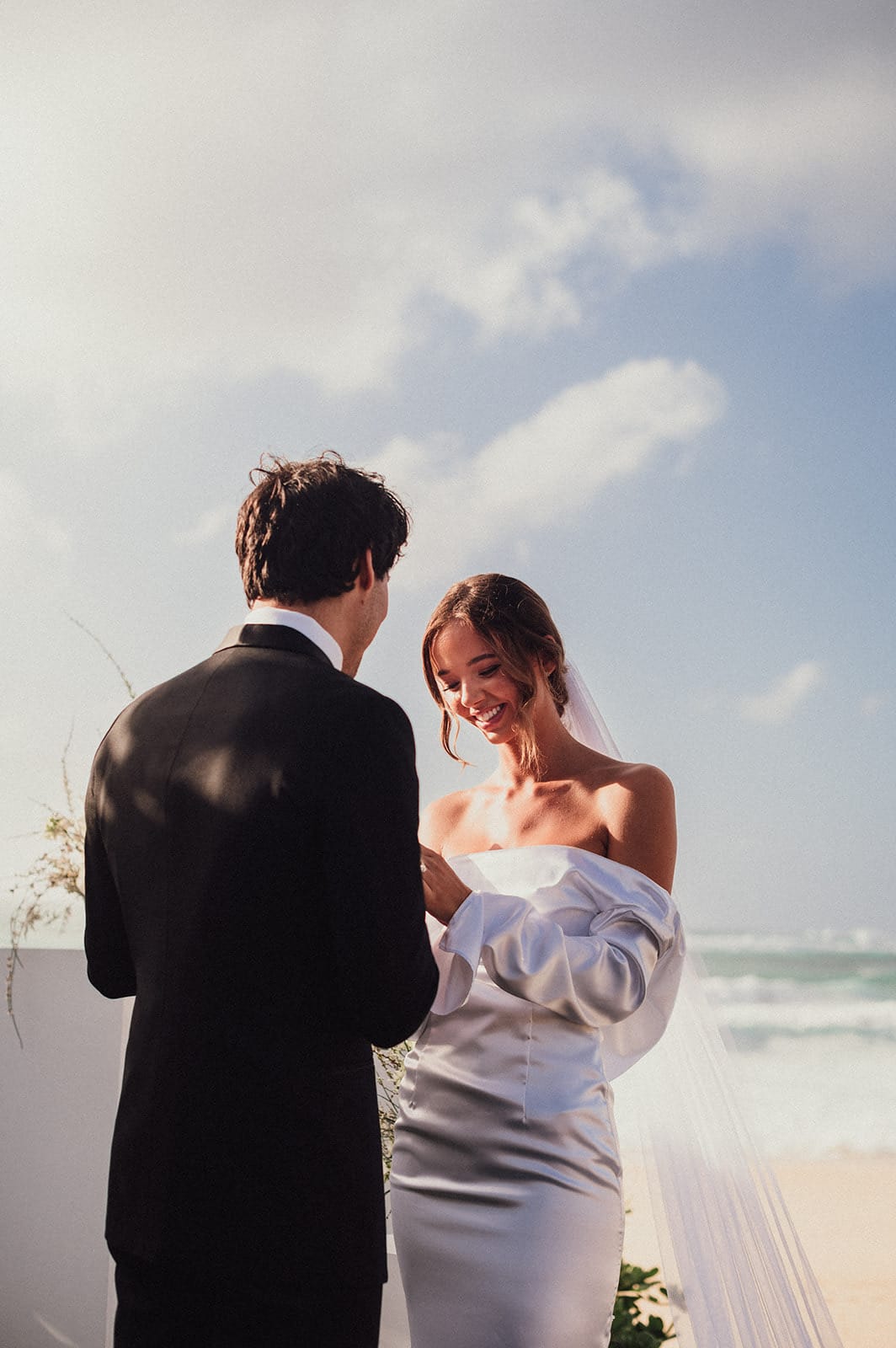 A couple face to face on their elopement day on the North Shore of Oahu, the ocean behind them