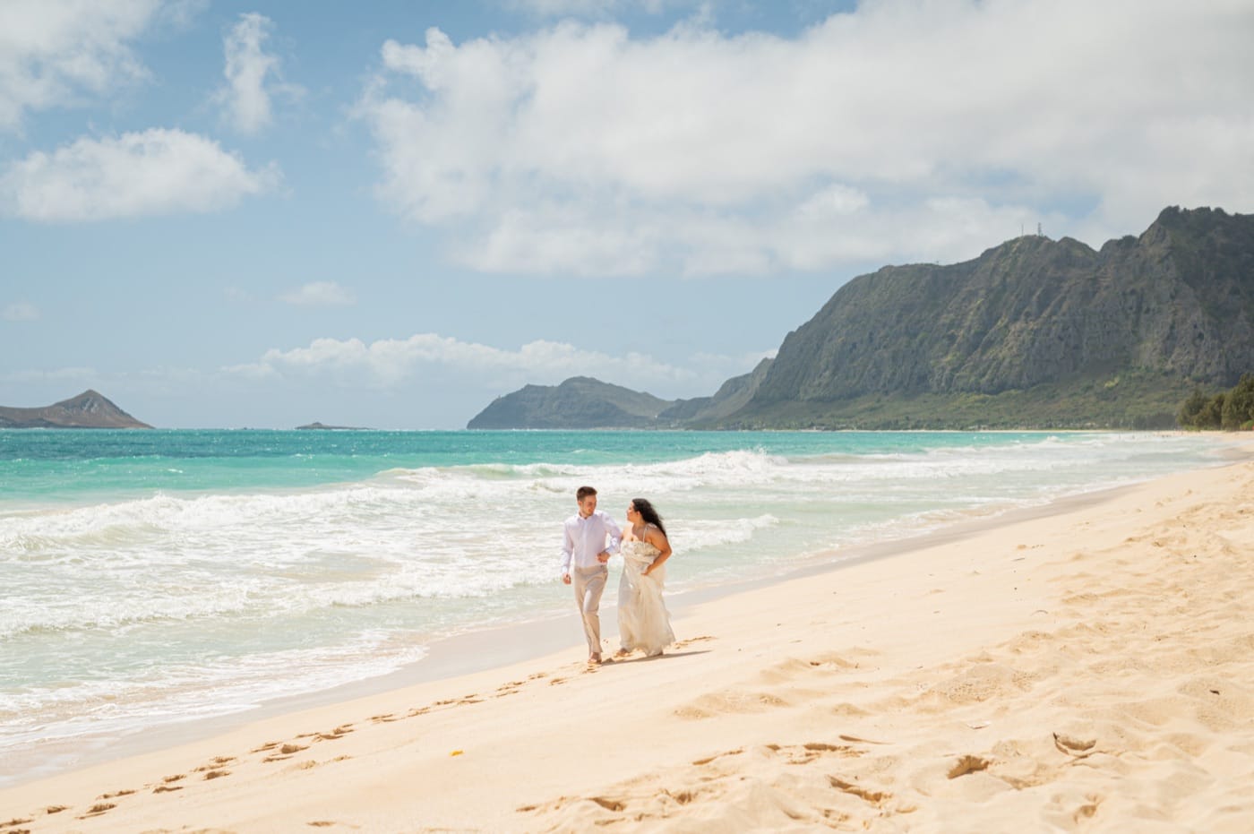 A couple walking away down Waimanalo Beach after their ceremony