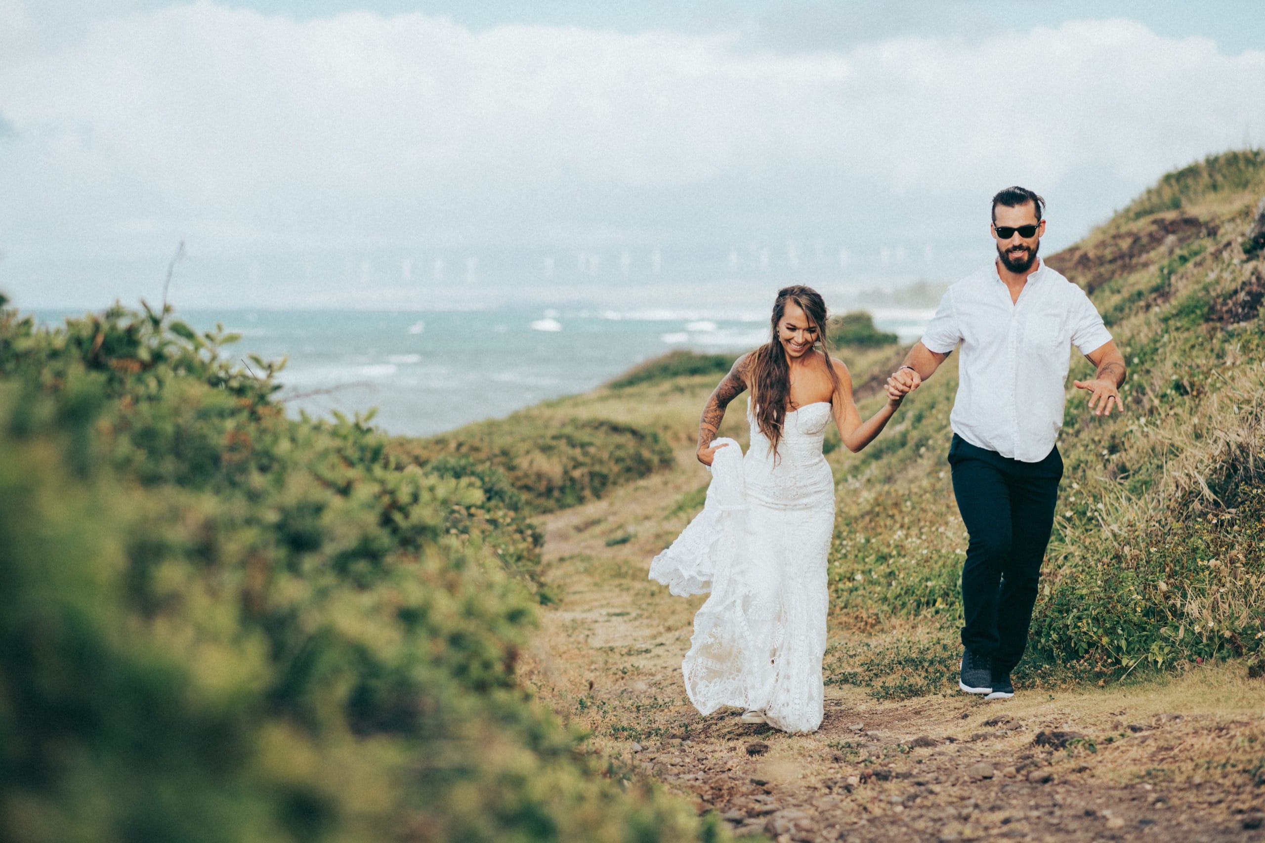 A couple walking a trail above the ocean on the North Shore of Oahu on their elopement day